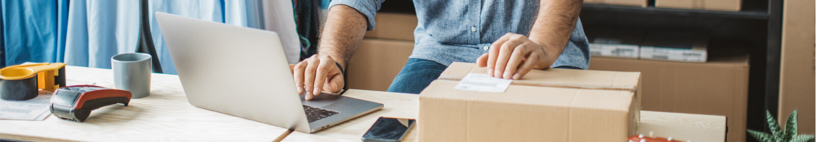 Close-up of a person's hands on a shipping box and a laptop