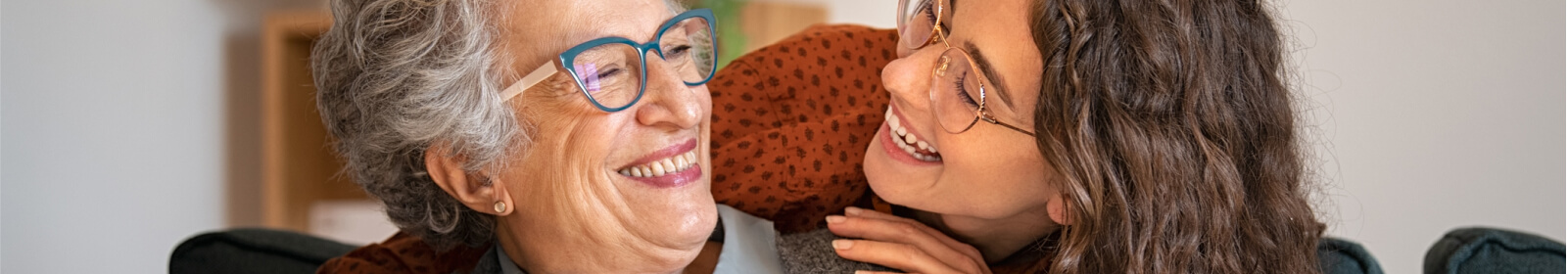 Younger and older women smiling at each other.